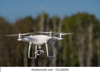 MOSCOW, RUSSIA - 24 September, 2017: a Phantom 4 Pro drone in flight, green trees in the background, selective focus on the drone. Phantom 4 Pro is a drone manufactured by the DJI company.