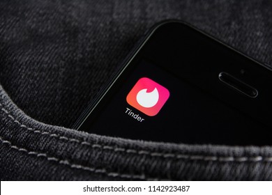 Moscow, Russia- 25 July 2018: Tinder application icon on smartphone screen. The smartphone lies in the front pocket of black jeans. Editorial use only.