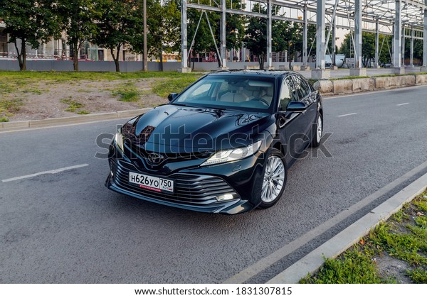 Moscow, Russia - 6 july 2020 - Toyota Camry parked\
next to a warehouse under construction. metal structures, green\
grass.