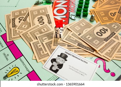 MOSCOW, RUSSIA - APRIL 10, 2019: Monopoly Board Game, Paper Toy Colorful Money, Two Dice And Red House And Game Attributes