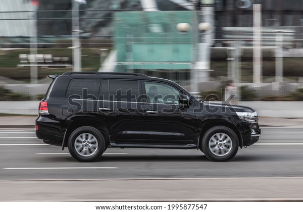 Moscow , Russia - April 2021: Fast moving Toyota\
Land Cruiser 200 on the city road. Black SUV rides on street. Japan\
4x4 auto in fast motion with blurred background. speeding in the\
city concept