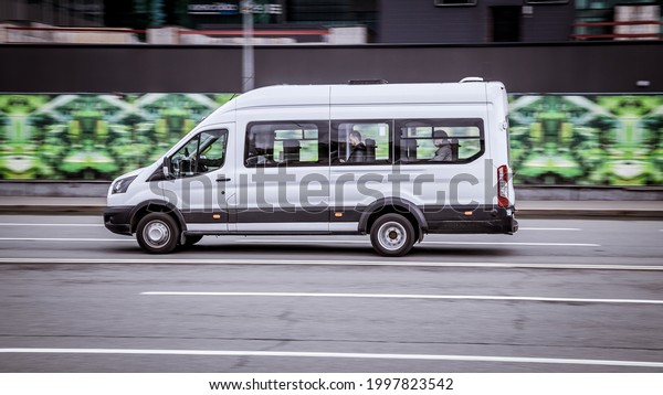 Moscow, Russia - April 2021: Ford Transit Fourth\
generation in the city street. Side view of white passenger van,\
light commercial\
vehicle