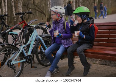 Moscow, Russia, April 29, 2018: Unidentified Kids In Helmets Eating Ice-cream On The Bench With Bicycles On Background On Sunny Spring Weekend In Moscow Park.