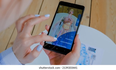 MOSCOW, RUSSIA - AUGUST 1, 2019. Woman using smartphone with augmented reality app: 3d educational anatomical human body system. Future, AR, anatomy, medical, science, technology healthcare concept