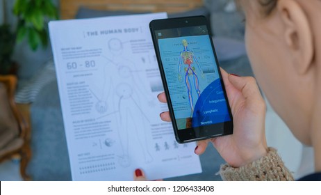 MOSCOW, RUSSIA - AUGUST 10, 2018. Woman using smartphone with augmented reality app - educational anatomy human body system. Future, medical and technology concept
