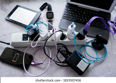 Moscow, Russia, August 2020: Many gadgets - smartphone, wireless headphones, laptop, smart watch, camera battery and e-book are charged on one power strip 