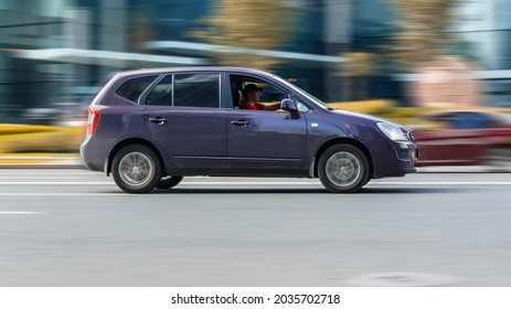 Moscow, Russia - August 2021: Kia Carens Second generation car in purple color fast speed drive on the asphalt city road. Kia Rondo on the road in motion, side view