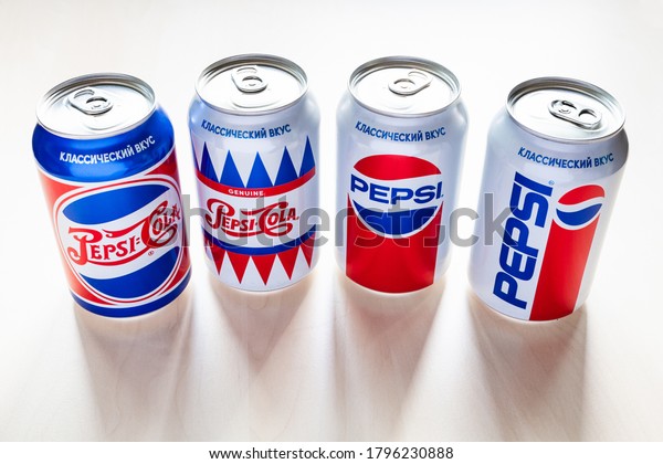 MOSCOW, RUSSIA - AUGUST 6, 2020: cans of Pepsi with design from the 40s, 50s, 80s and 90s of the 20th century on light brown wooden table. Pepsi is carbonated soft drink manufactured by PepsiCo