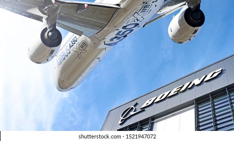 MOSCOW, RUSSIA - CIRCA AUGUST, 2015: Boeing company lettering logo against Airbus A350 modern airplane flying on blue sky background wide view usa europe competition trade war concept