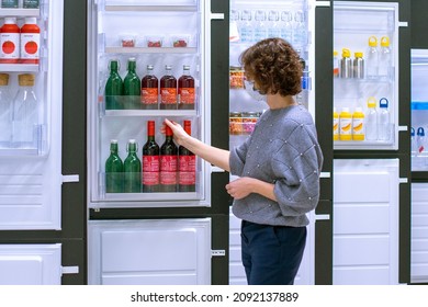 MOSCOW, RUSSIA - DECEMBER 16, 2021: A Young Woman Alone In The Ikea Store Stands Near The Refrigerators And Chooses Food