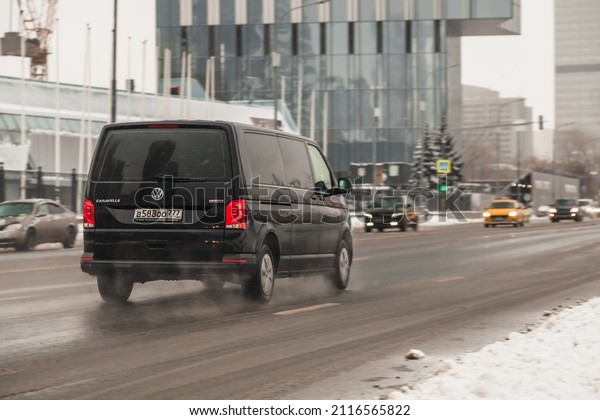 Moscow, Russia - December 2021: Fast moving\
Volkswagen Transporter T6 on winter city road. Black van rides on\
wet slippery street. Commercial auto in fast motion with blurred\
background.
