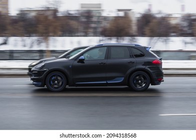 Moscow, Russia - December 2021: Two Black Porscha Cayenne Cars Racing At High Speed On Winter City Road With Motion Blur Effect