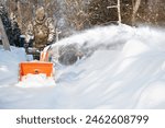 Moscow, Russia - february 08 2024: The self-propelled snow-plough blower. The man in warm clothes winter gloves instead of the big shovel has chosen a self-propelled engine snowplow white snow