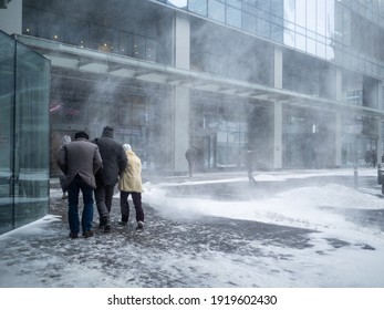 Moscow. Russia. February 12, 2021. Natural disasters. People walk along the building through a blizzard with heavy snowfall. A snow cyclone covered the city.