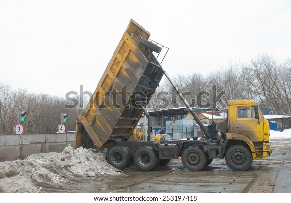MOSCOW, RUSSIA - February 13, 2015: Unloading\
dirty snow from the body of the truck KAMAZ in negotable on\
snow-melting point,\
Moscow