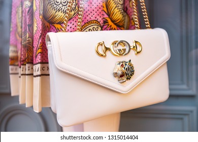 Moscow, Russia - February 2019: Beige Women's Gucci Cross Bag With Gold Chain Close-Up On Background Of Dress With Print From New Collection.