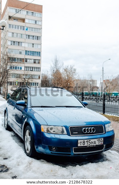 Moscow, Russia - February 2022: Car Audi A4 Avant\
Quattro B6 in blue color parked on snowy parking lot. Front side\
view of old estate vehicle on the background of multi storey\
residential house