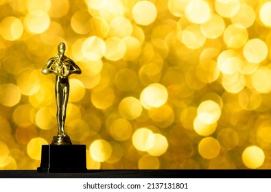 Moscow, Russia - February, 2022: Hollywood Golden Oscar Academy award statue against yellow gold lights background.