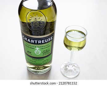 Moscow, Russia - February 3, 2022: Liqueur Glass And Bottle Of Green Chartreuse Liqueur On Pale Table. The Liqueur Has Been Made By The Carthusian Monks N France Since 1737