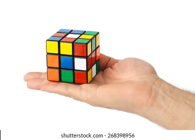 MOSCOW, RUSSIA - January 07, 2015: Hand And Rubik's Cube Puzzle Isolated On The White Background. Cube Was Invented By A Hungarian Architect Erno Rubik In 1974.