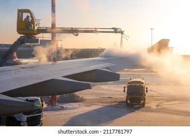 Moscow, Russia - January 12, 2022: Sheremetyevo International Airport. De-icing an aircraft wing. Process of spraying anti-icing white fluid rear part of  wing of a plane at the airport at sunrise 