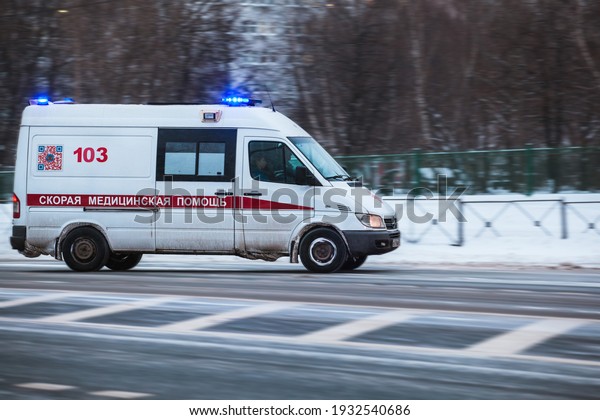 Moscow,\
Russia - January 14 2021: An ambulance with flashing lights on is\
driving along the street. Snow is all around. Side view, motion\
blur. Residential area. Translation:\
Ambulance