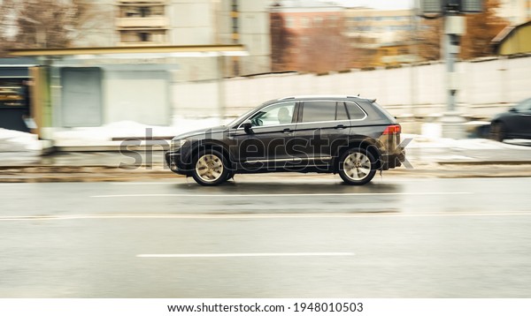 Moscow, Russia - January 2021: fast moving SUV rides\
on a winter city road. A car on wet slippery road in motion.\
Overspeed in city concept. Fast moving black Volkswagen Tiguan with\
dirt on the body