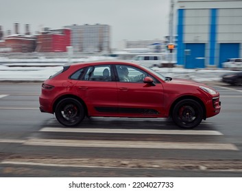 Moscow, Russia - January 2022: Red SUV Car Porsche Macan Rides In The City Street With Motion Blur. Side View Of Fast Moving Crossover Car On Winter Road. Compliance With Speed Limits On The Road