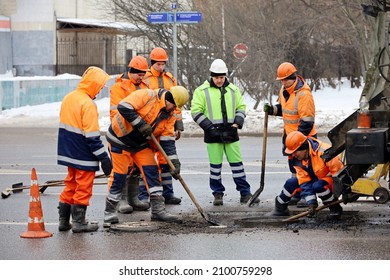 Moscow, Russia - January  2022: Workers Fill Up The Pit On Road With Asphalt, Men With The Shovels. Street Works In City, Sewer Repair