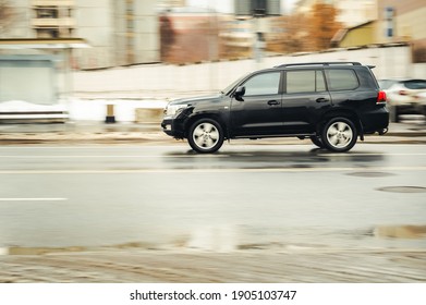 Moscow, Russia - January 29, 2021: fast moving SUV rides on a winter city road. A car on wet slippery road in motion. Overspeed in city concept. Fast moving black Toyota Land Cruiser 200