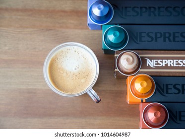 MOSCOW, RUSSIA - JANUARY 31, 2018: Illustrative And Editorial Image Of Nespresso Boxes And Coffee Capsules On Top Of Each Box And Cup Of Coffee On Wooden Background