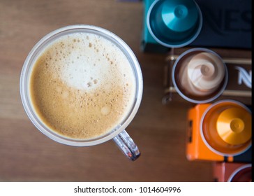 MOSCOW, RUSSIA - JANUARY 31, 2018: Illustrative And Editorial Image Of Nespresso Boxes And Coffee Capsules On Top Of Each Box And Cup Of Coffee On Wooden Background