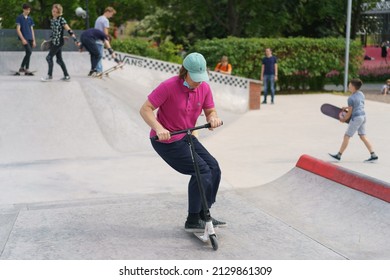 Moscow, Russia - July 1, 2020: Teenager Performs Trick In Skate  Park During Coronavirus Pandemic. Push Scooter. Extreme Sports Is Popular Among Youth. Group Of Young Sportsmen. They Skateboarding 