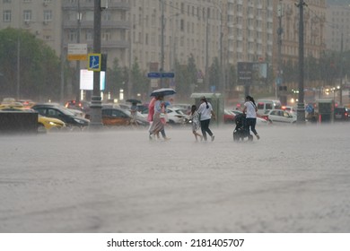 Moscow, Russia - July 10, 2022: Raining Day In City At Summer. Wet People With Cchildren Running. Texture Of Strong, Fresh And Powerful Water Drops And Sprays. Tropical Storm