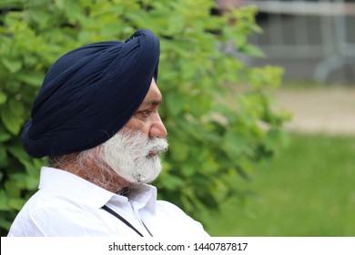 Moscow, Russia - July 2019: Portrait Of Bearded Indian Sikh In A Turban Sitting On A Bench In Alexander Garden, Profile View