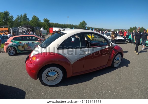 Moscow, Russia - June 01, 2019:  Tuned red and\
white volkswagen beetle parked on the street, Scirocco wrapped\
stays at background