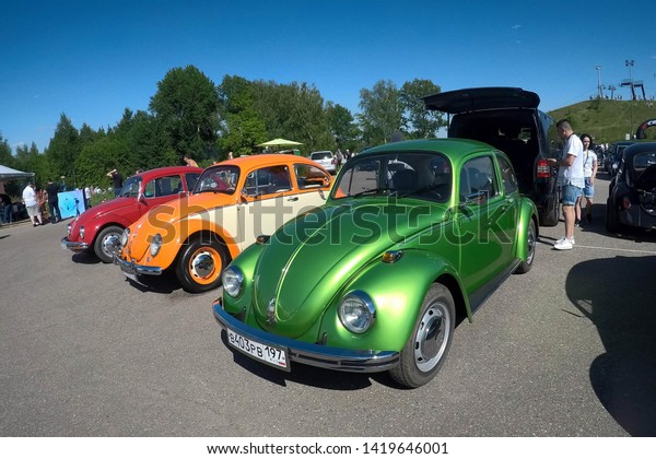 Moscow, Russia - June 01, 2019: Volkswagen beetle\
(Kaefer)  parked in row on the open parking on the street. Green,\
orange and red vw bugs