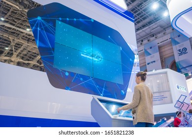 MOSCOW, RUSSIA - JUNE 05, 2019: Smart Expo. Woman Using Electronic Kiosk And Watching Presentation On Large Interactive Wall Display At Technology Exhibition