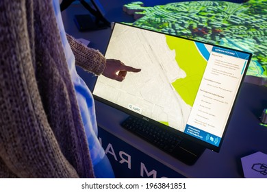 MOSCOW, RUSSIA - JUNE 05, 2019: Technology exhibition. Woman hand using touchscreen display of kiosk with city street map app in dark room - close up. Navigation, journey, sci-fi concept