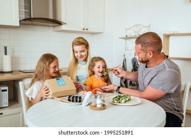 MOSCOW, RUSSIA - JUNE 11, 2021: The Family Is Having Lunch In A Bright Apartment Eating Sushi. T