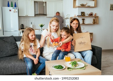 MOSCOW, RUSSIA - JUNE 11, 2021: The Family Is Having Lunch In A Bright Apartment Eating Sushi. 