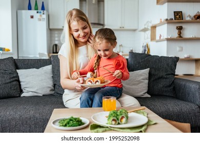 MOSCOW, RUSSIA - JUNE 11, 2021: The Family Is Having Lunch In A Bright Apartment Eating Sushi. 