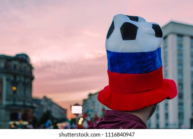 Moscow, Russia - June 20, 2018: Soccer Fan With Big Ball Hat Colored Like Russian Flag On Sunset Background In Moscow.