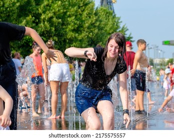 Moscow. Russia. June 26, 2021. Young girls in wet clothes play in the cool water jets of the city fountain on a hot summer day.