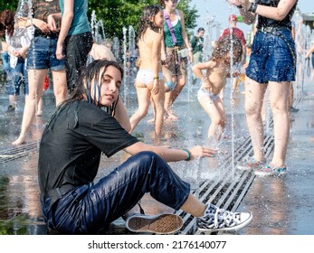 Moscow. Russia. June 26, 2021. Portrait of a beautiful young girl in wet clothes bathing in a city fountain on a hot summer day.