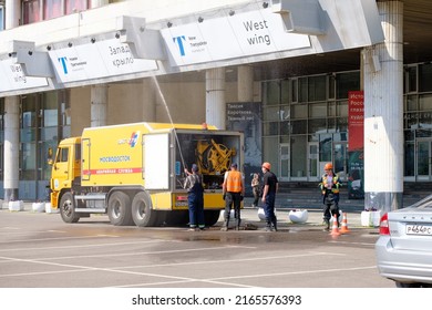 Moscow. Russia. June 9, 2022. A Public Utility Worker Washes The Facade Of A Building With A Water Jet From A Hose On A Sunny Summer Day. Public Service Work In Moscow.