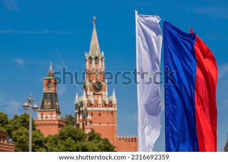 MOSCOW, RUSSIA - JUNE : The national flag of the Russian Federation against the background of the Kremlin's Spasskaya Tower on Red Square is the Russian Tricolor. The holiday is Russia Day.