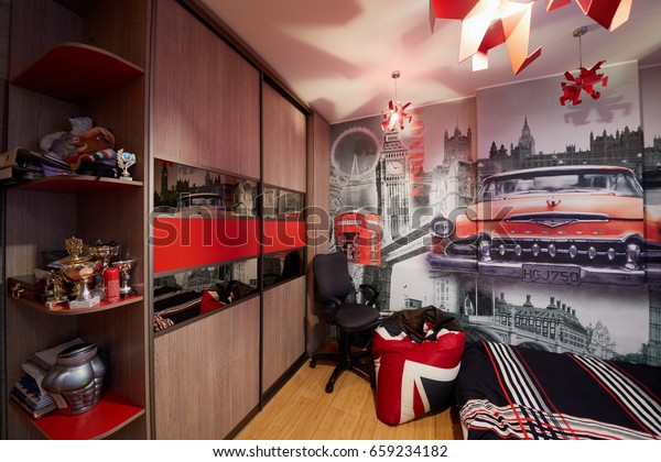 MOSCOW, RUSSIA - MAR 1, 2017: Interior of living\
room of young man, walls decorated with photo wallpaper with London\
sights and red car.