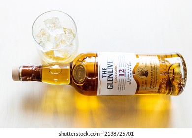 Moscow, Russia - March 20, 2022: glass and lying bottle of 12 years old Glenlivet single malt Scotch whisky on pale table. Glenlivet distillery was founded in 1824 and has operated continuously since