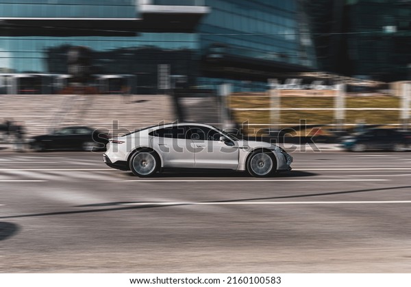 Moscow, Russia - march 2022: Gray Porsche Taycan\
Turbo S luxury electric auto driving on the street. Electric\
vehicle model is moving\
outdoors
